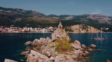 Areal shot over the St. Nedjelja Church in Montenegro.4K drone shot of the orthodox church and the landscape in Montenegro.Summer atmosphere. Othodox church on the small island.Picturesque landscape.