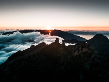 Drone 'dan çekilen, Pico Grande' den çekilen, güneş ışığıyla yıkanan bir manzara, bulutların altındaki görkemli dağlar.