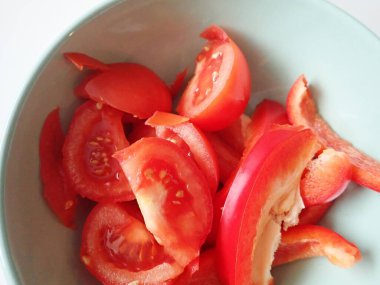 Bir kasede dilimlenmiş kırmızı domates ve biber.