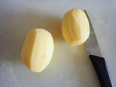 İki çiğ patates soyulmuş ve pişirilmek üzere kesilmiş.