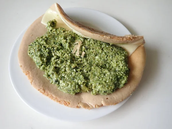 Tabağında yeşil pesto olan bir porton krep.