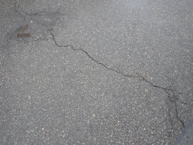 Islak asfalt yolda yağmurdan sonra kırılan çatlaklar