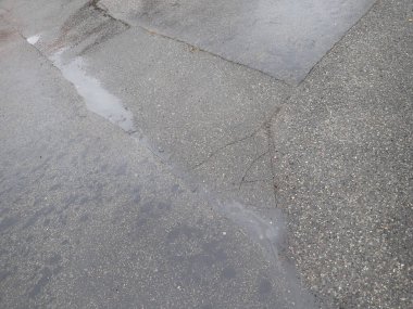 Islak asfalt yolda yağmurdan sonra kırılan çatlaklar