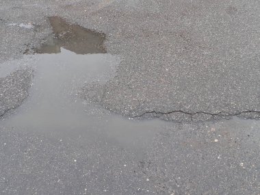 Islak asfalt yolda yağmurdan sonra kırılan çatlaklar