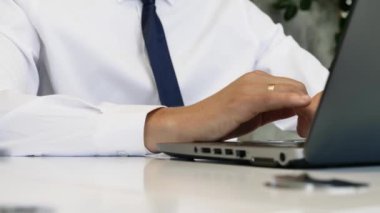 Ofisteki dizüstü bilgisayarda çalışan bir adam. Eller klavyede yazı yazıyor. Ofis işi.