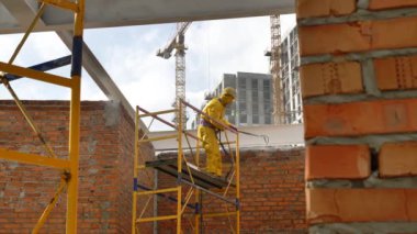 Bir adam metal yapılar boyuyor. Metal için ateş tedavisi.