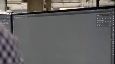 Bir adam çift monitörde bir kurgu yazılımı ya da uygulama üzerinde çalışıyor. Yaratıcı medya ajansı