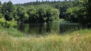 Bir adam gölde şişme bir teknede otururken balık yakalar..