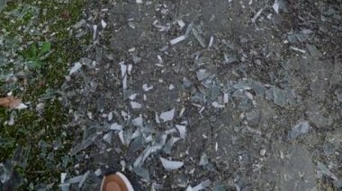 krasovki 'li bir adam yolda kırık camların üzerinde yürür. Bacaklarını kapat.