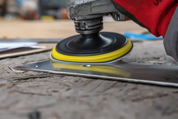 Bir adam atölyede metal öğütmek için özel bir alet kullanır. Bir endüstriyel işçiyle birlikte ağır bir makine fabrikasının içinde. Bir adam öğütme makinesiyle metal öğütüyor ve bir sürü kıvılcım uçuyor..