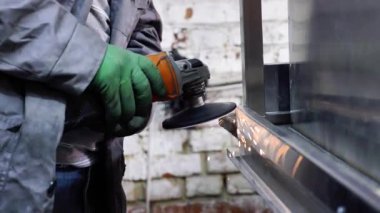 Bir adam atölyede metal öğütmek için özel bir alet kullanır. Bir endüstriyel işçiyle birlikte ağır bir makine fabrikasının içinde. Bir adam öğütme makinesiyle metal öğütüyor ve bir sürü kıvılcım uçuyor..