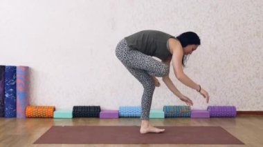 Atletik kadın ışıkla dolu bir odada yoga yapıyor, kadın yoga pozları veriyor, amuda kalkıyor..