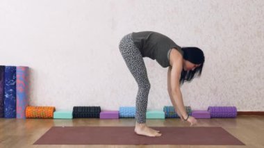 Atletik kadın ışıkla dolu bir odada yoga yapıyor, kadın yoga pozları veriyor, amuda kalkıyor..