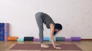 Atletik kadın ışıkla dolu bir odada yoga yapıyor, kadın yoga pozları veriyor, amuda kalkıyor..