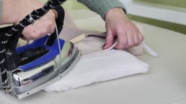  Kadın bir terzi, bir ürünü ütülemek için ütü masasında çalışır. Bir terzi, fabrikada ya da moda stüdyosunda dikiş diktiği bir ürünü ütüler..