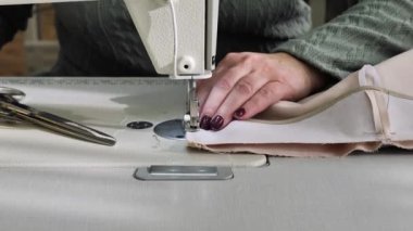 Dikiş. Yakın plan. Terzi dikiş makinesine kumaş dikiyor. Dikiş makinesinin iğnesi hareket halinde. Giysi fabrikasında çalışma süreci.
