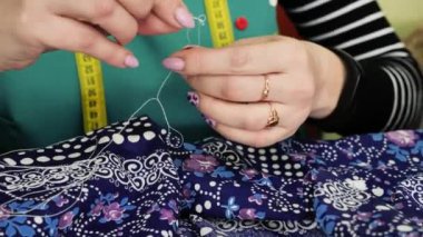 Bir kadın kumaş ürününe iplik dikiyor. Ön hazırlık: bir iğne ve iplikle kumaşa katılmak. Bir kadın kendi elleriyle dikiş diker..