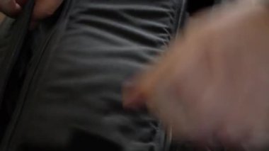 Adam çantasına makineli tüfek koyuyor. Siyah çantalı ve silahlı.