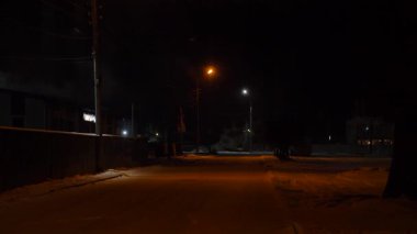 Şehir karlı kış gecesi sahnesi sokak lambalarıyla aydınlatılmış boş karlı bir yol..