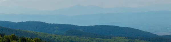 stock image Panorama landscape of a forest and mountains in the background.