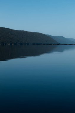 Güzel bir dağ manzarası ve pürüzsüz yüzeyi olan sakin bir su..