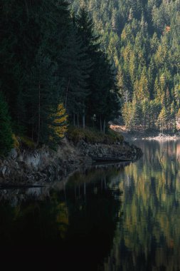Büyük gölü ve yüzeyinde yansımaları olan rodoplu dağlardaki güzel sonbahar manzarası..