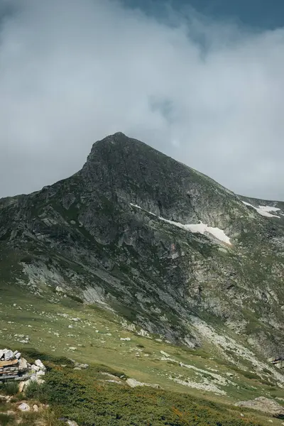 Sisin altındaki kayalık dağ zirvesi ve uzaktaki bulutlar.