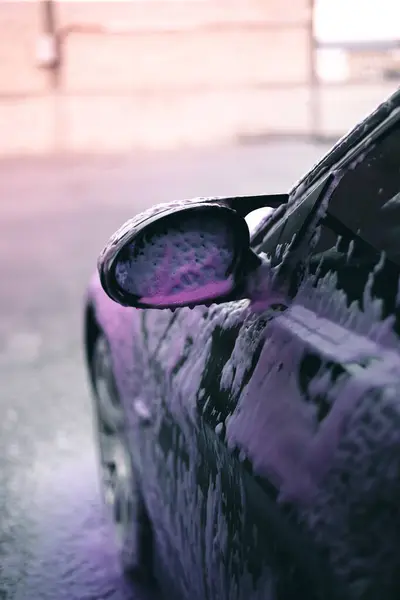 stock image Purple soap foam all over the car waiting to be washed.