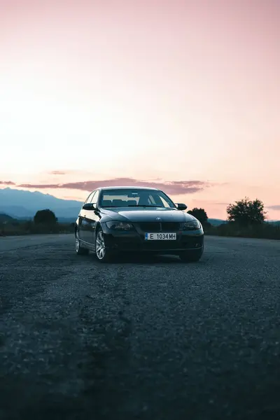 Bulgaristan - 07: 23: 2024: Renkli bir geçmişe sahip boş bir havaalanında bir BMW E90 'ın destansı günbatımı çekimi.