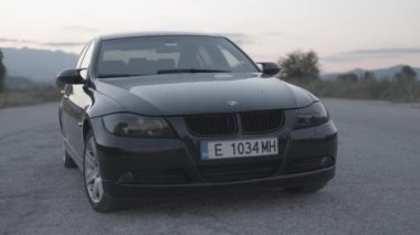 Bulgaristan - 10 22 2024: Günbatımında terk edilmiş bir havaalanı pistinin ortasında siyah e90 BMW. Düzenlemesiz olarak Clog 3 'te çekildi.