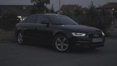 Bulgaristan - 10 22 2024: Gün batımında açık bir otoparkta siyah Audi. CLog 3 'te 4K 60fps. Düzenleme yok.