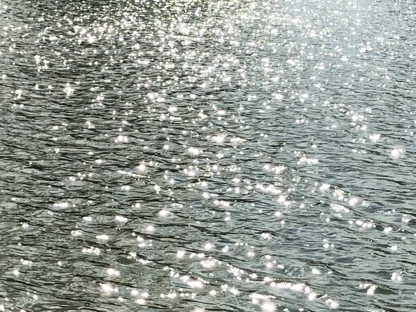 Water surface with ripples and sun rays reflections. Water surface with brightness in the distance.Real photo.