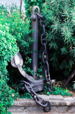 Old heavy anchor between green trees stock photo