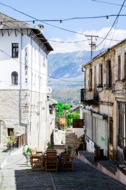 Gjirokaster 'da restoran masaları olan dar bir sokak, stok fotoğrafı.