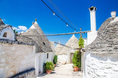 Alberobello, İtalya 'da konik çatı evleri ve lambaları olan beyaz cadde