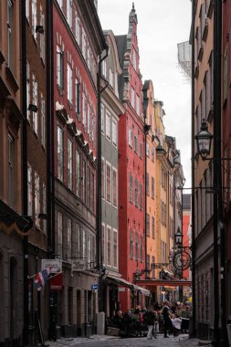 Stockholm, İsveç - Eylül 2022: Gamla Stan 'de kaldırım taşı yolu olan renkli eski kasaba caddesi manzarası.