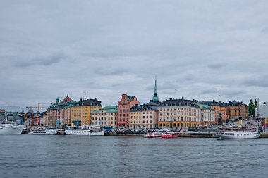 Stockholm, İsveç - Eylül 2022: Rıhtıma bakan eski renkli binalar ve şehrin ufuk çizgisi Stadsholmen, Gamla Stan