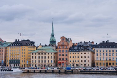 Stockholm, İsveç - Eylül 2022: Rıhtıma bakan eski renkli binalar ve şehrin ufuk çizgisi Stadsholmen, Gamla Stan