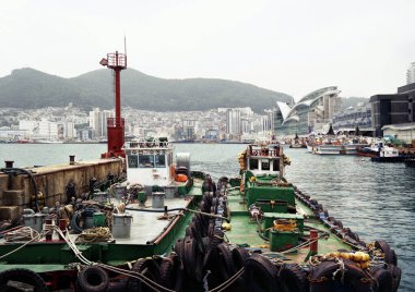 Busan, Güney Kore - Mayıs 2019 Busan Limanı ve eski balıkçı tekneleri ve bulutlu şehir manzarası ve manzarası