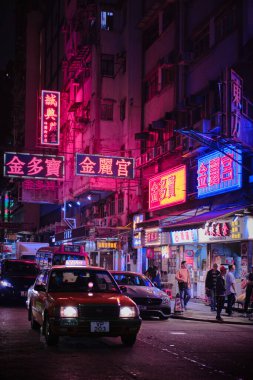 Mong Kok, Hong Kong - 12 Nisan 2023: Geleneksel kırmızı taksi ve renkli neon ışıklı tabelalar