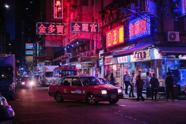 Mong Kok, Hong Kong - 12 Nisan 2023: Geleneksel kırmızı taksi ve renkli neon ışıklı tabelalar