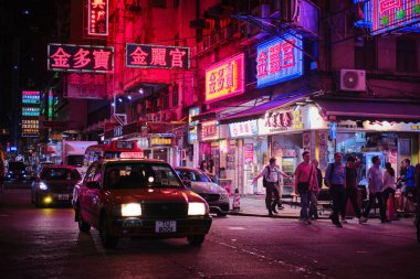Mong Kok, Hong Kong - 12 Nisan 2023: Geleneksel kırmızı taksi ve renkli neon ışıklı tabelalar