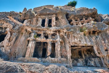 Antalya, Türkiye - 18 Temmuz 2023: Antik Tlos kentinin antik kaya mezarları, karmaşık bir şekilde yamaçlara oyuldu