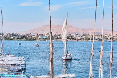 Luxor, Mısır - 26 Aralık 2023: Geleneksel motor feribotları ve Felucca yelkenlileri Nil Nehri kıyısında demirlediler