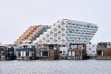 Netherlands, Amsterdam - April 10, 2024: Sluishuis modern residential building  in the district Ijburg, designed by Bjarke Ingels Group, BIG clipart