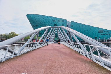 Hollanda, Amsterdam - 08 Nisan 2024: NEMO Büyük yeşil renkli gemi Renzo Piano tarafından tasarlanan ve yaya köprüsü kanalı ile bilim müzesi inşa eden bina.