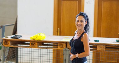 İşteki kadın kameraya bakıyor ve gülümsüyor.