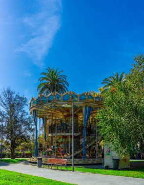 Etrafı yemyeşil manzaralarla ve güneşli, mavi gökyüzü altında palmiye ağaçlarıyla çevrili.