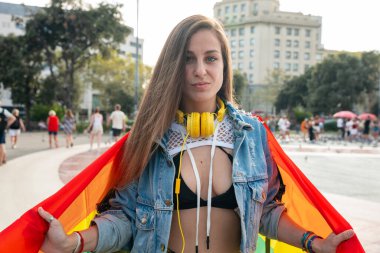 Lgtbi bayrağı taşıyan genç bir kadın savaşıyor ve gururundan güç gösteriyor. Kavram: yaşam tarzı, gurur, açık hava