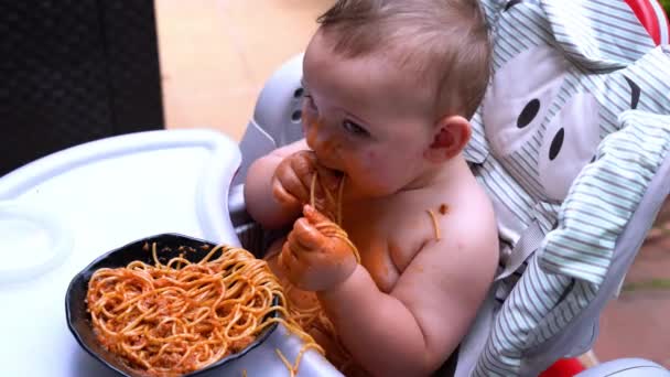 スパゲッティを食べながら ハッピーで甘い赤ちゃんが混乱しています 自家製パスタとトマトソースで楽しいドリンク — ストック動画